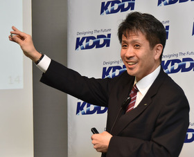 写真1：KDDIのビジネスIoT推進本部ビジネスIoT企画部で部長を務める原田圭悟氏。1円玉サイズのLTE-M通信モジュール「KYW01」を手に取って説明している