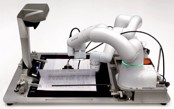 写真1：ロボットアームを使って契約書などへの捺印を自動化できるシステム「RPA＆COBOTTA オフィス向け自動化支援」を使って書類への捺印を行っている様子（出典：デンソーウェーブ）