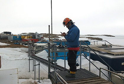 写真1：昭和基地の屋外でスマートフォンを操作しローカル5G通信を利用する観測隊員（出典： 国立極地研究所）